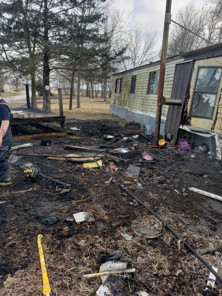 An out of control fire burnt trash right next to a single side trailer.