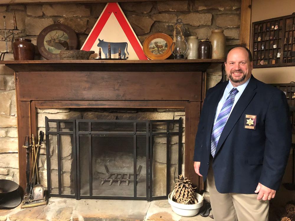 Sheriff Steve Cox with the fireplace mantel from the Joseph Cox cabin. The mantel was handed down to Steve from his grandfather Manford Cox.