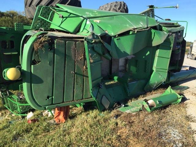 Green semi-tractor and trailer crash resulting in the vehicle being flipped on its side and dented.